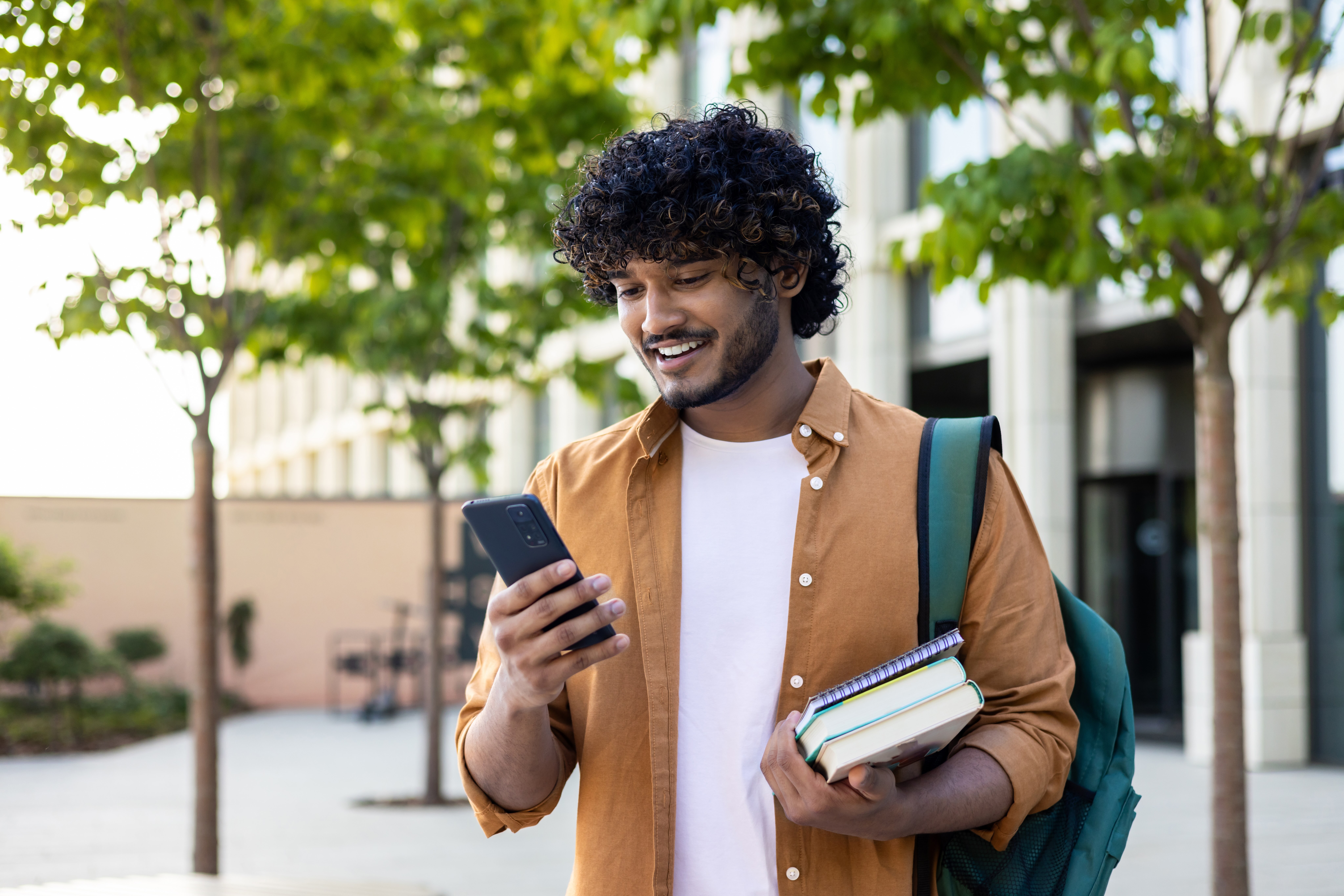 man on cellphone holding educational books, looking excited