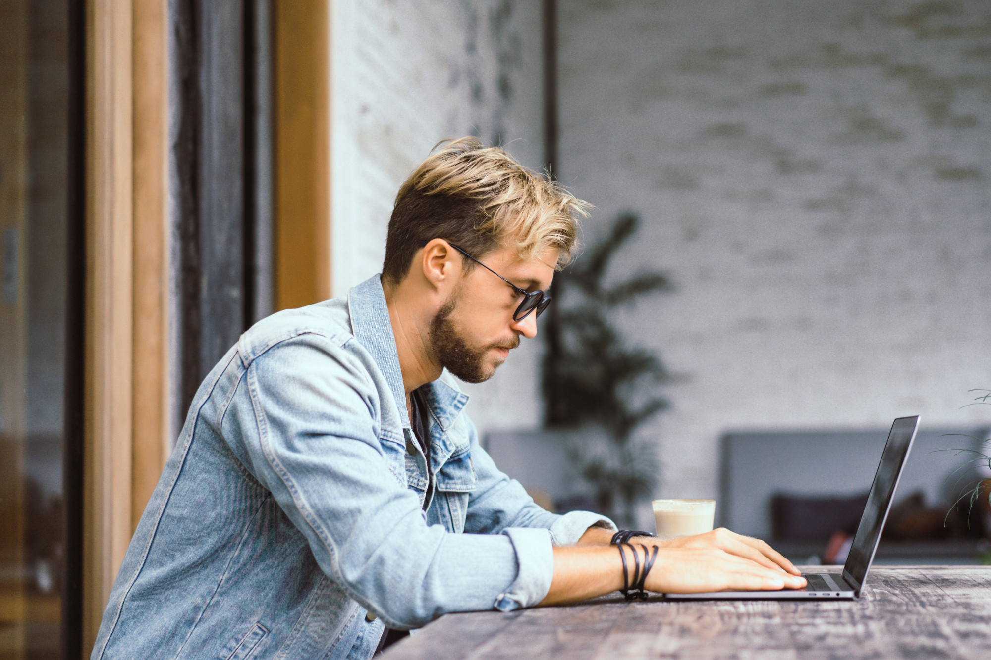 Young attractive business man in a cafe works for a laptop, drinks coffe