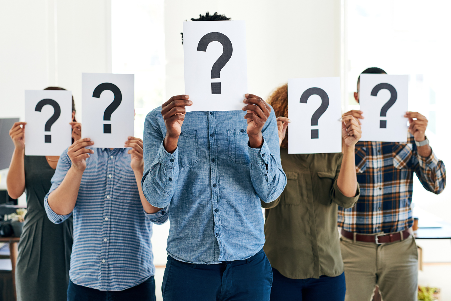 Shot of a group of businesspeople holding questions marks in front of their faces