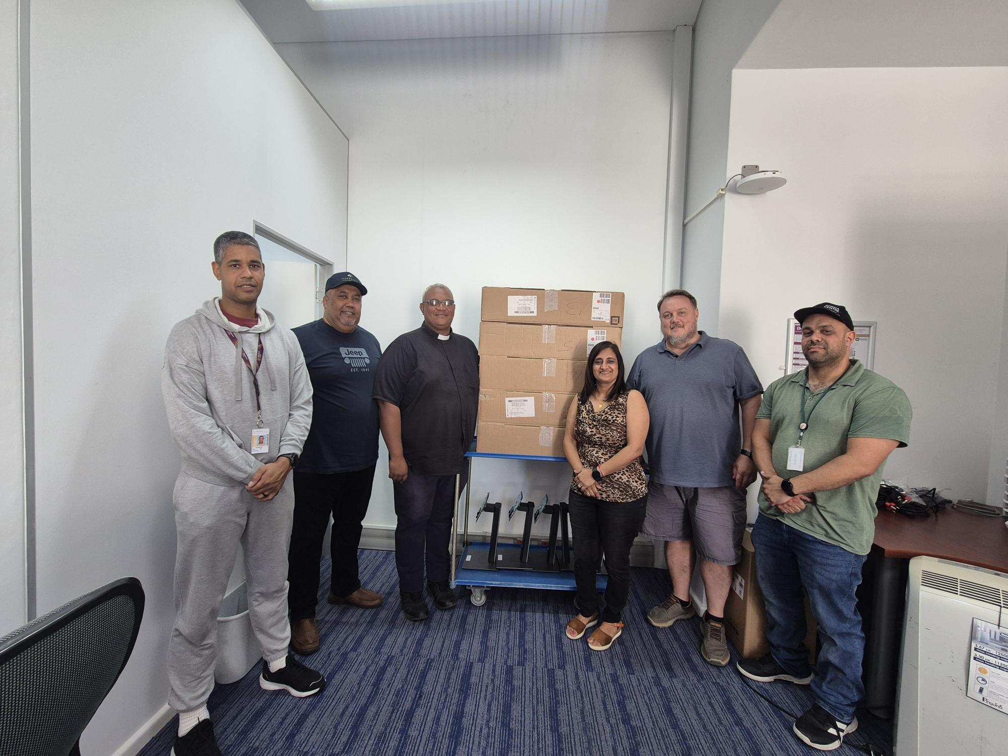 The Rector of St Mary's, the Rev Canon Enrico Heuvel, with Mrs Heena Jivan, Head of IT and Operations of EMS, standing on both sides of a trolley with donated computers, and IT team members (f.l.t.r.) Denver Anthony, Thurlo Muller, Chris Bosman and Remé du Plessis.