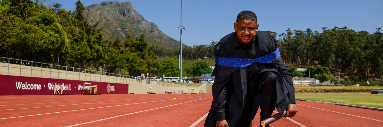 Dyan Buis photographed with his Master’s degree at the Coetzenburg Athletics Stadium in Stellenbosch.