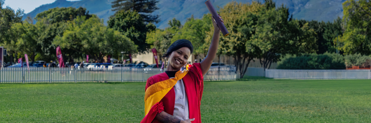 Dr Allison Matroos photographed holding her degree outside the Coetzenburg Centre