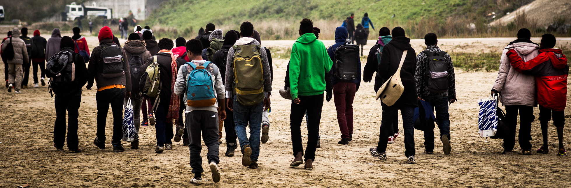 A group of African migrants on the move with the backs to the camera.