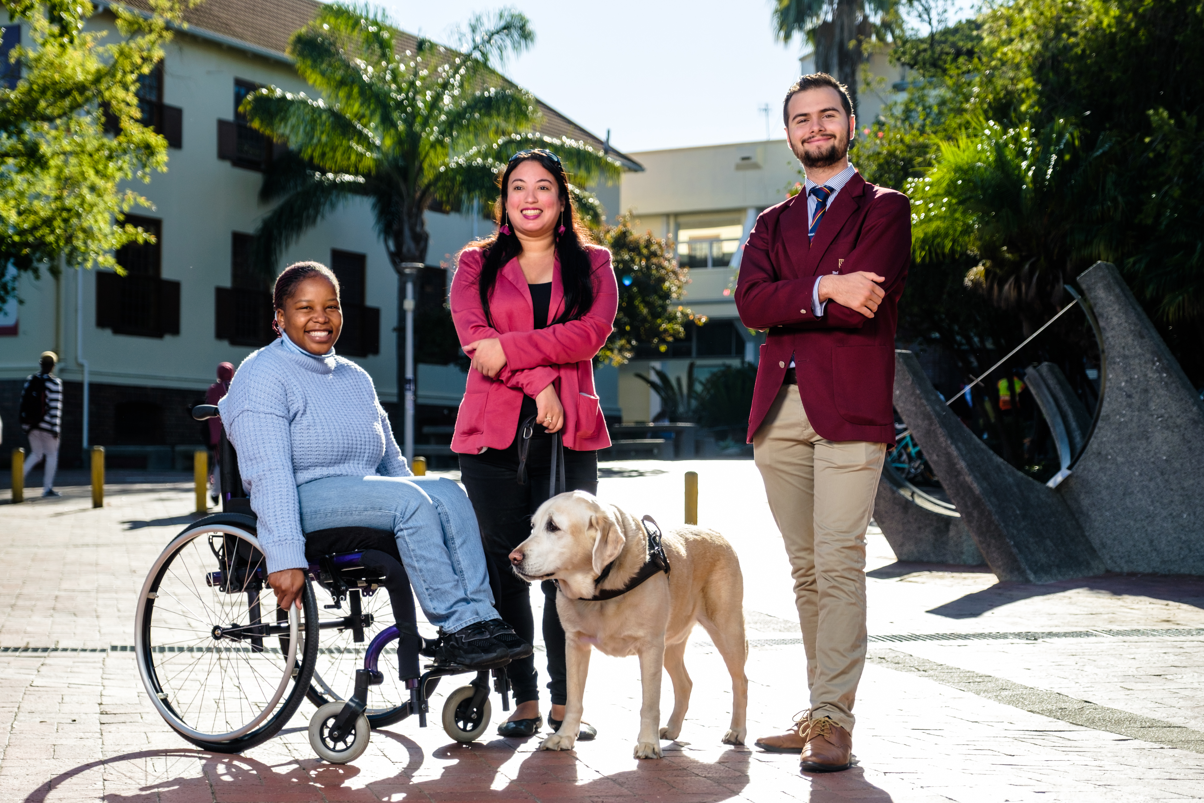 A photo of three students with visible and invisible disabilities at SU standing on the Rooiplein