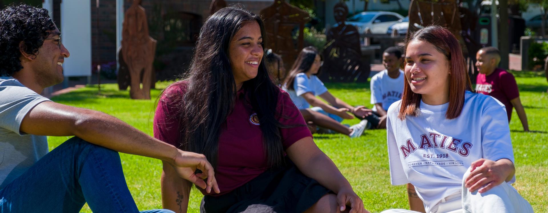 Students in Maties clothing sitting on the lawn on the Stellenbosch Campus