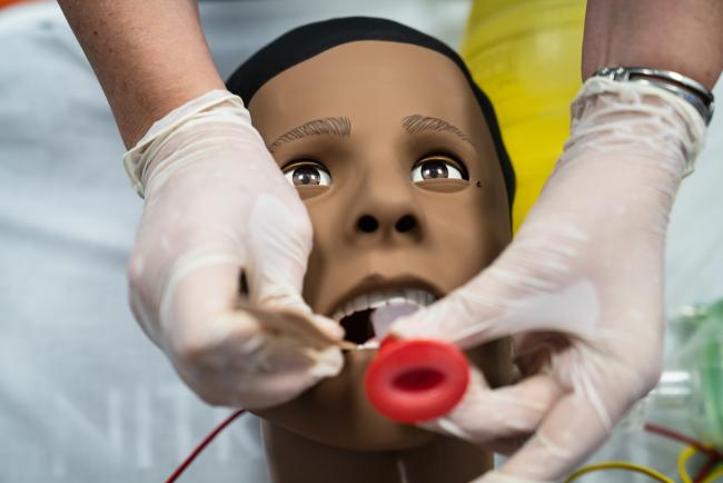 A medical student inserts a breathing tube into a high-fidelity simulation manikin