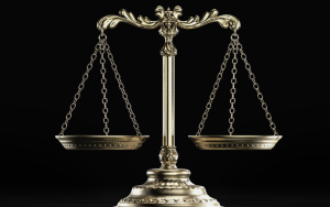 An illustration of Libra scales of justice against a black background.