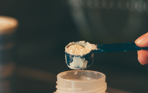 Baby formula and a milk bottle photographed on a brown table.