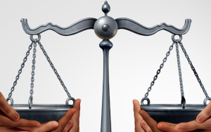 A picture of peoples’ hands balancing the scales of justice.