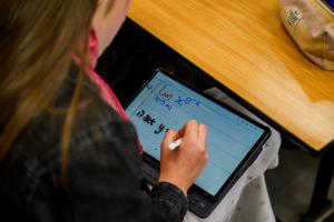 Science student taking notes on an electronic device in a maths lecture