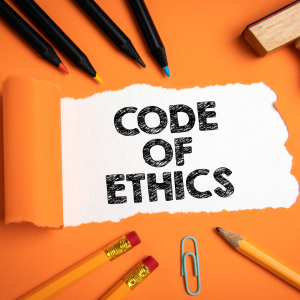Photo with the words Code of Ethics on it and pencils and pens as well as a paper clip lying on the paper.
