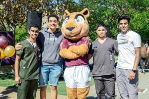 Photo of four students at Tygerberg standing with Pokkel, SU's squirrel mascot