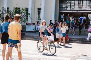student riding a bike in front of the krotoa building