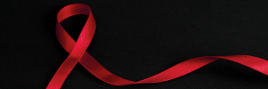 A red ribbon on a black background symbolizes HIV and AIDS awareness.