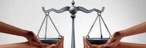 A picture of peoples’ hands balancing the scales of justice.